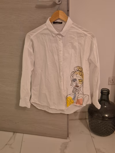 White shirt with face graphic by SHE PARIS — pre-loved on Thrifted.mt